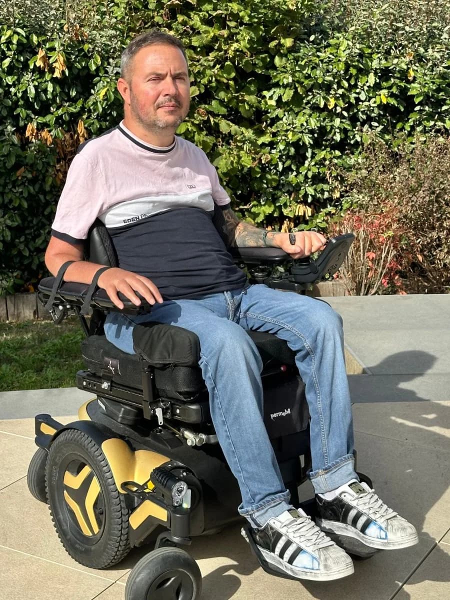 Julien, cofondateur, dans son fauteuil roulant au jardin